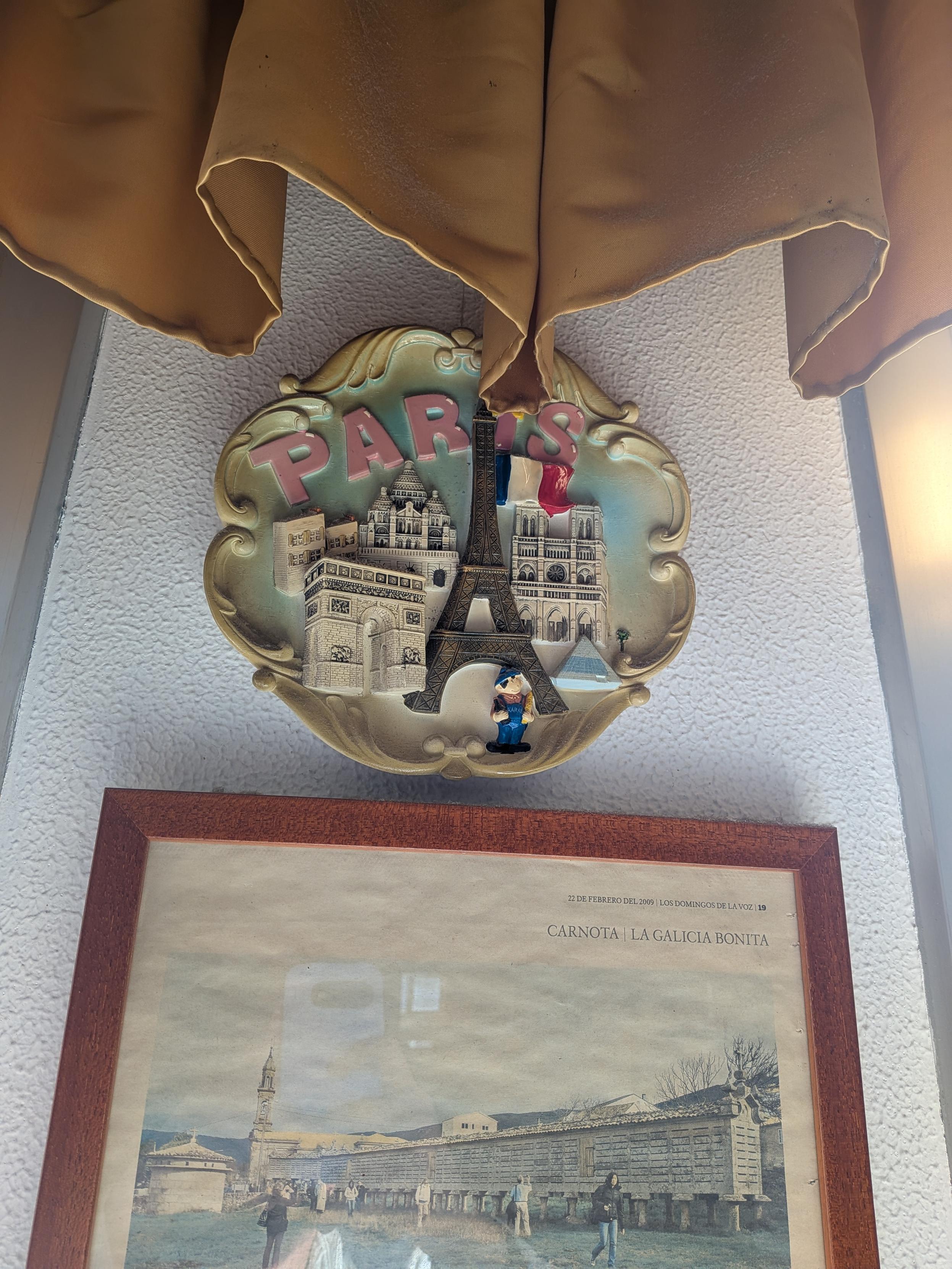 Plato souvenir con colores desvanecidos de París, reseñando varios monumentos en relieve y un monigote que parece una versión francesa de Súper Mario.